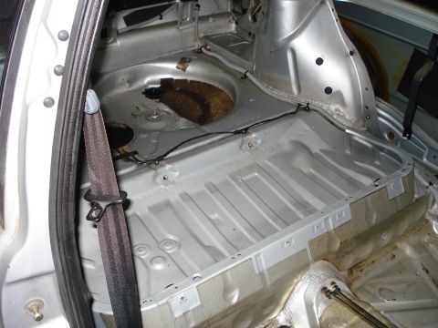 1985 Volkswagen GTI - The bare metal interior of a car's trunk, with a seatbelt visible.