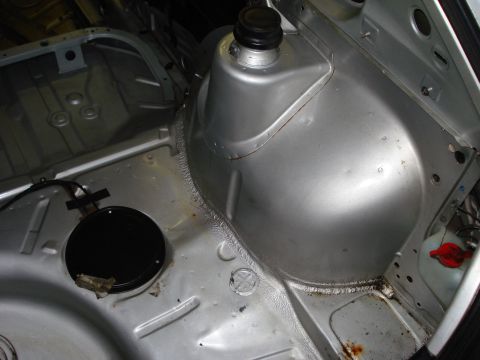 1985 Volkswagen GTI - The interior of a car's trunk area shows the metal structure around the wheel well and floor.