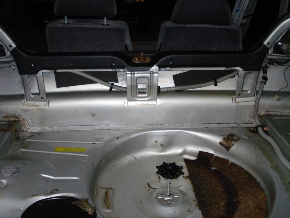 Interior of a car trunk, showing spare tire well and rear seats