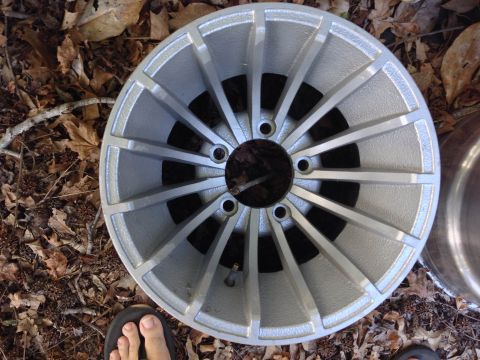 1979 Ford Bronco - A single alloy wheel is shown lying on the ground amidst fallen leaves.