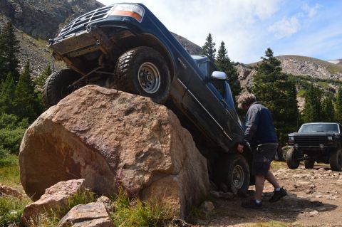 1983 Ford Bronco - Ford Bronco navigating a difficult off-road obstacle with another vehicle in the background.