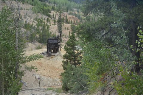 1983 Ford Bronco - An old mine building sits on a hillside surrounded by trees and rocky terrain.