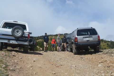 1983 Ford Bronco - A group of people stand near off-road vehicles on a rocky mountain trail.