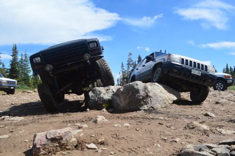 1983 Ford Bronco - Two off-road vehicles tackle a challenging rocky trail on a sunny day.