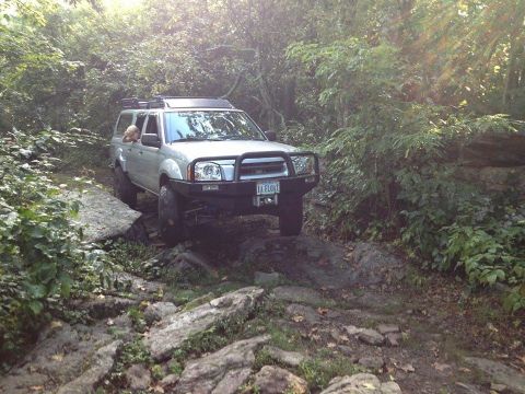 2003 Nissan Frontier - This 2003 Nissan Frontier is shown off-roading on a rocky path, equipped with a custom front bumper and roof rack.