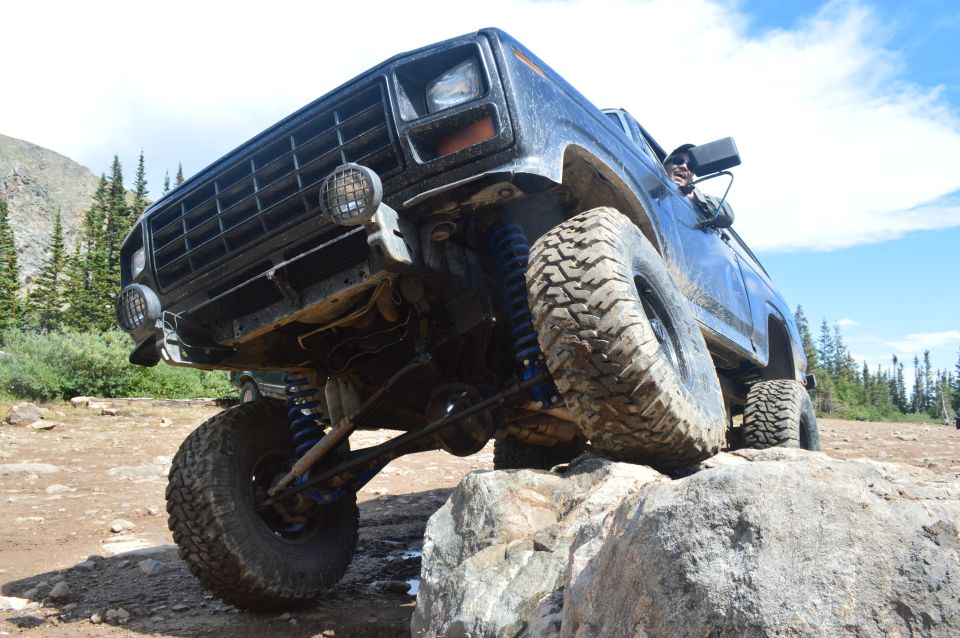 Dark blue off-road SUV with large tires climbing over rocks