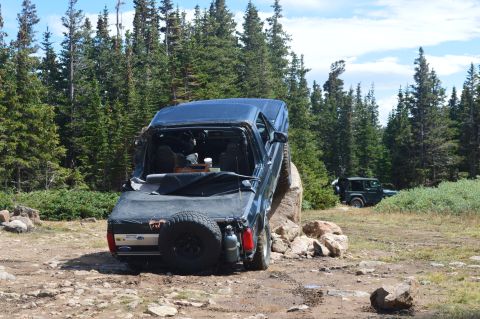 1983 Ford Bronco - A dark blue SUV navigates a rocky trail with another vehicle in the background.
