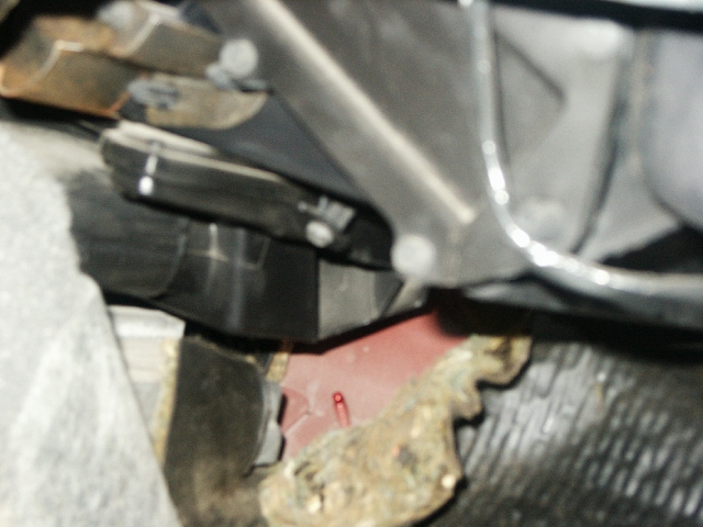Undercarriage view of vehicle parts, including red painted metal and black plastic components