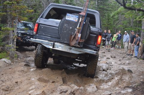 1983 Ford Bronco - A group watches as a modified Ford Bronco tackles a challenging off-road obstacle.