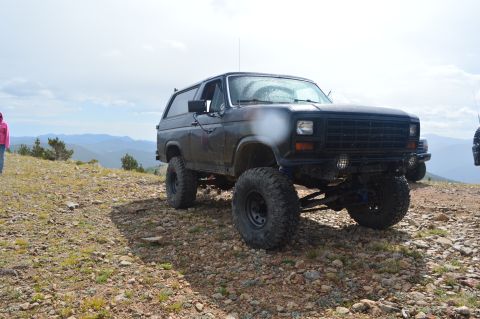 1983 Ford Bronco - Modified Ford Bronco sits on a mountain trail, with a second vehicle visible in the background.