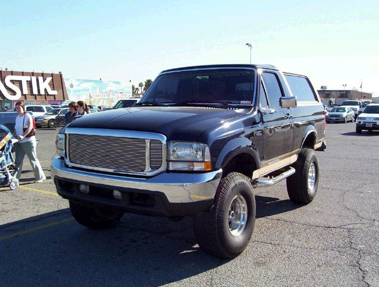 Dark blue Ford Bronco with chrome grille and side steps, lifted suspension