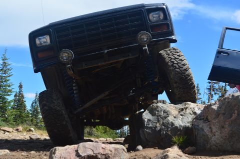 1983 Ford Bronco - An off-road SUV navigates a rocky terrain, demonstrating its suspension and tire grip.