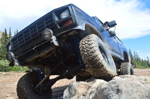 1983 Ford Bronco - Ford Bronco navigating a rocky off-road trail with its tires on large boulders.