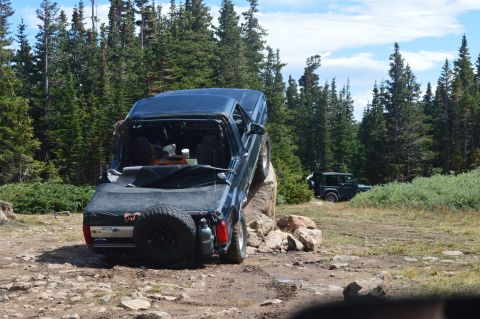 1983 Ford Bronco - An off-road vehicle navigates a challenging rocky terrain with another SUV visible in the distance.