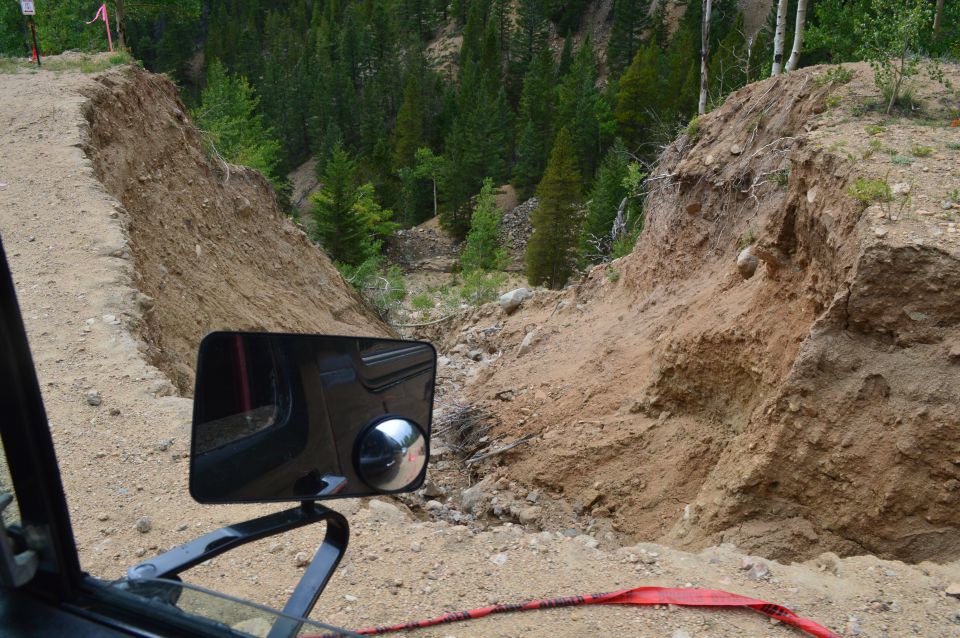 View from inside a vehicle looking at a steep, eroded dirt embankment on an off-road trail