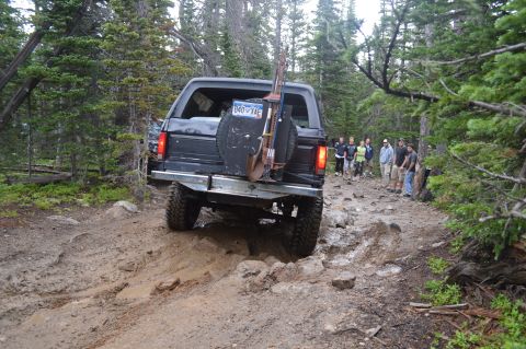 1983 Ford Bronco - A group of people watch a black Ford Bronco navigate a challenging off-road trail.