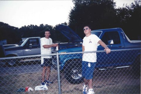 1982 Ford Bronco - Two men stand by a blue 1982 Ford Bronco, its hood raised, suggesting a moment of maintenance or admiration.