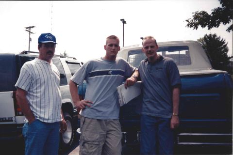 1982 Ford Bronco - Three men pose for a photo next to a dark blue SUV with a white removable top.