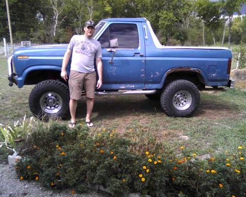 1982 Ford Bronco - A man stands next to a blue 1982 Ford Bronco, its exterior and lifted stance.