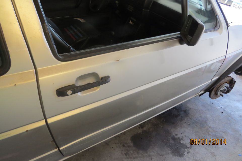 White car door with black handle and side trim, viewed from a high angle
