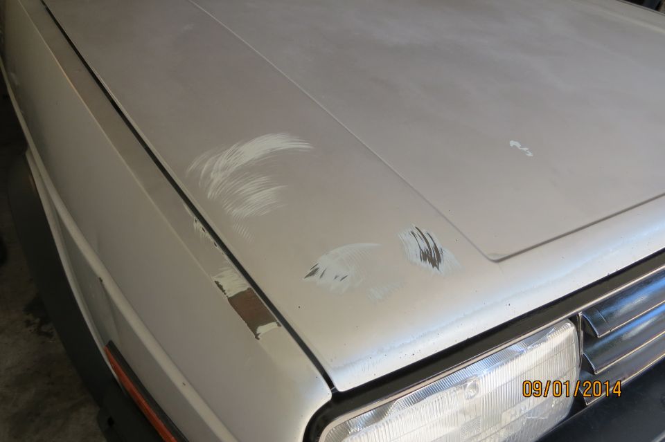 Silver car hood with some dents and scratches