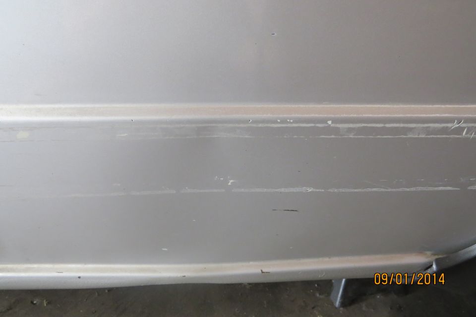 Close-up of a silver car door with visible scratches and scuff marks along a body line