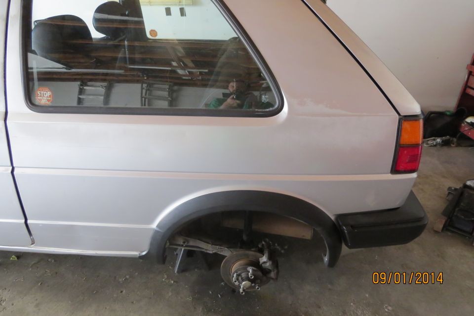 Rear quarter view of a silver Volkswagen Golf Mk2 with rear wheel removed. Interior visible through window