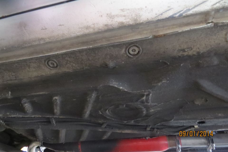 Underside view of a car with visible rust and undercoating