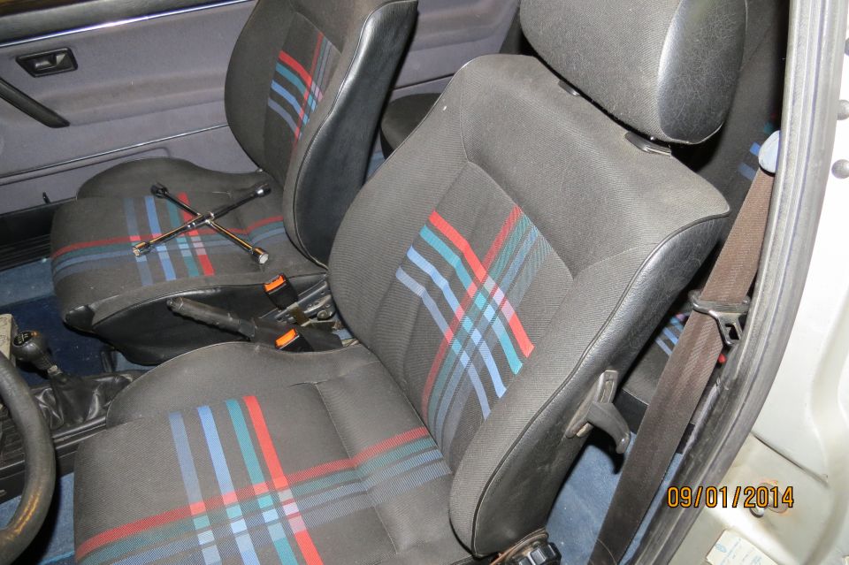 1985 Volkswagen GTI interior with plaid seats and a lug wrench on the passenger seat