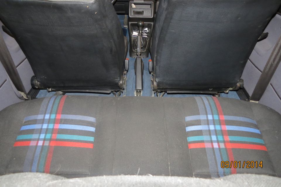 Back seat and front seats of a car, showing plaid seat inserts and a manual shifter