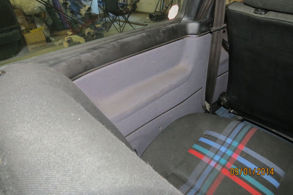 1985 Volkswagen GTI interior showing striped seat fabric, grey door panel, and seatbelt