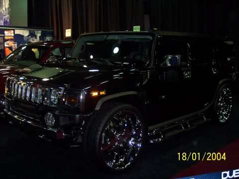 2001 Ford Taurus - A black Hummer H2 is shown with large chrome wheels and side steps, parked indoors.