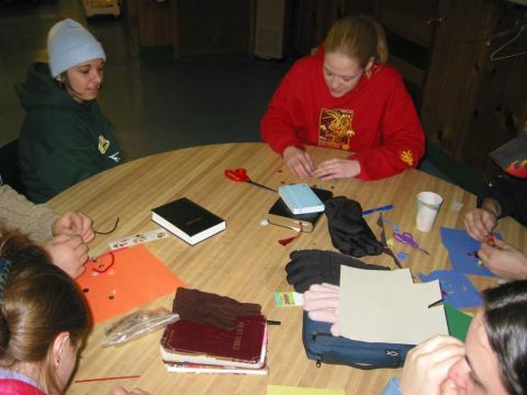 2001 Ford Taurus - A group of individuals are seated around a table, actively participating in a craft project, with supplies spread out before them.