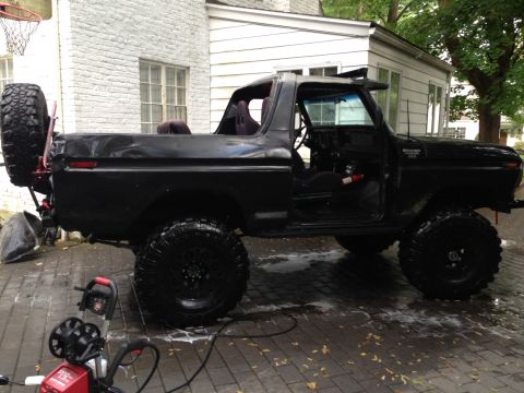 1979 Ford Bronco - This black 1970s Ford Bronco features a spare tire mounted on the rear and appears to be undergoing cleaning.