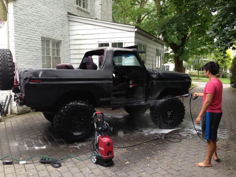 1979 Ford Bronco - Pressure washing a black 1979 Ford Bronco in front of a house.