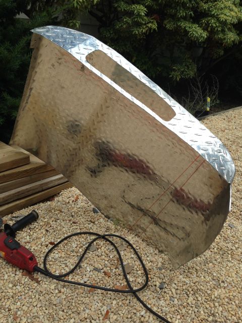 1979 Ford Bronco - A metal panel with diamond plate trim and cutouts sits on gravel next to a power tool.
