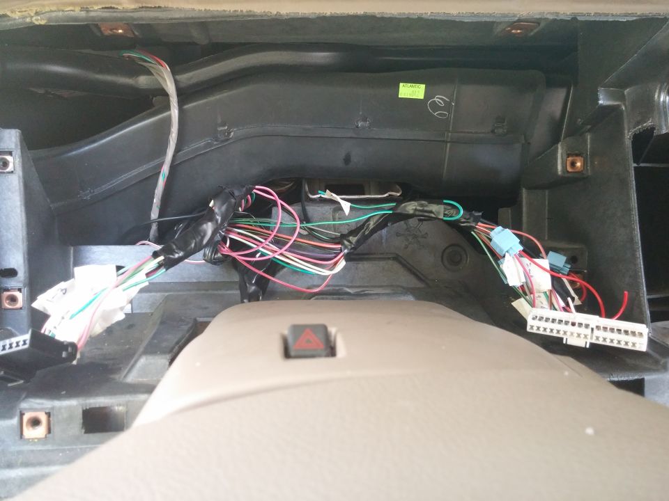 Car dashboard wiring mess with many colored wires and connectors exposed