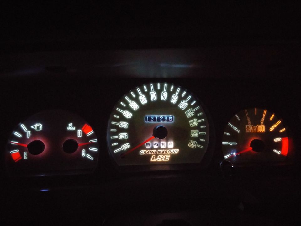 Car dashboard with illuminated gauges showing 131266 miles and 'GRAND MARQUIS LSE' text