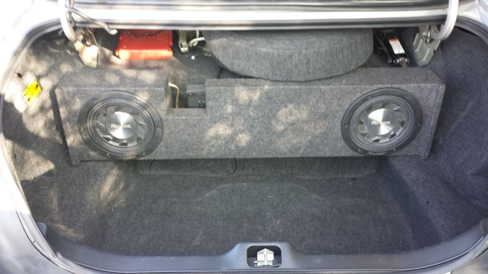 Car trunk with a dual subwoofer box, spare tire, and jack