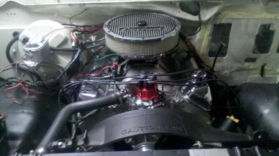 Engine compartment with chrome air cleaner and red distributor cap. Visible text 'CAUTION'