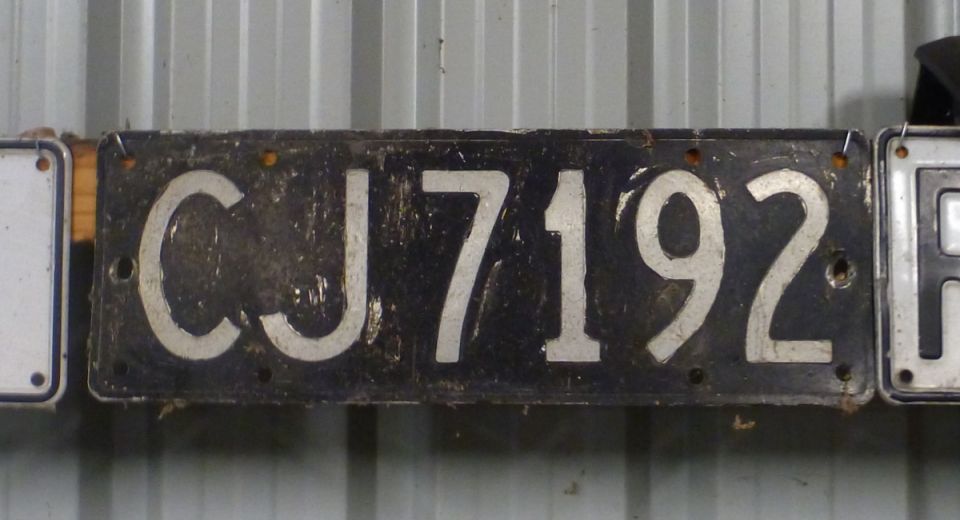 Old license plate with CJ 7192 on it, next to another plate