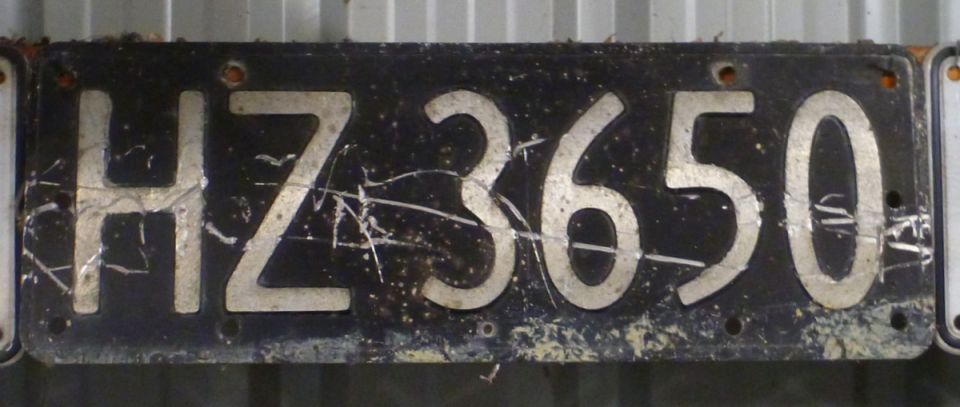 Black license plate with white characters HZ3650, scratched and worn