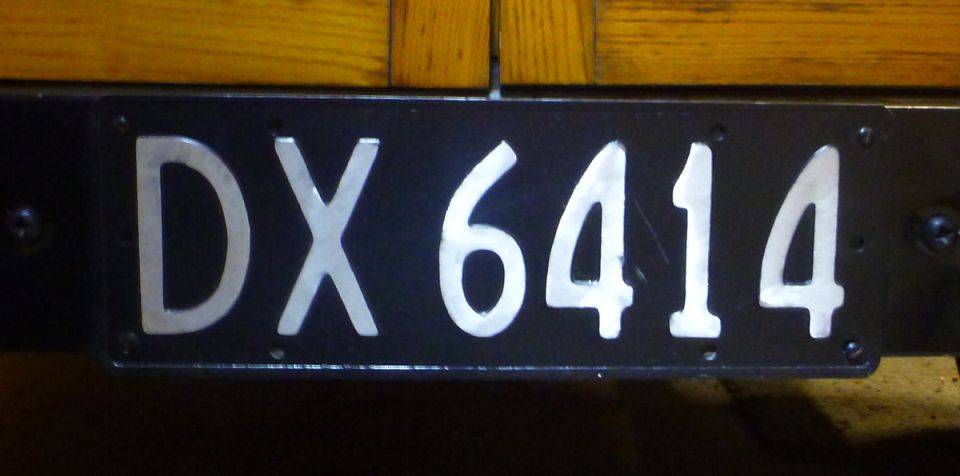 Black license plate with silver characters DX 6414
