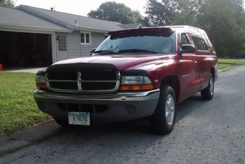 2006 Ford E350 - This red Dodge Dakota pickup truck, seen from a 3/4 front angle, is parked in front of a house.