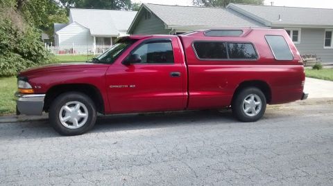 2006 Ford E350 - Side view of a red Dodge Dakota pickup truck with a camper shell.
