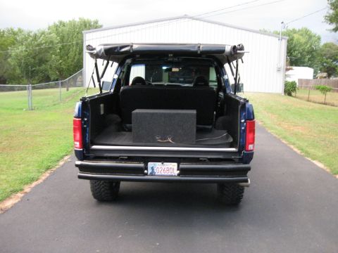 1982 Ford Bronco - Rear view of a blue Ford Bronco with a soft top and aftermarket bumper.
