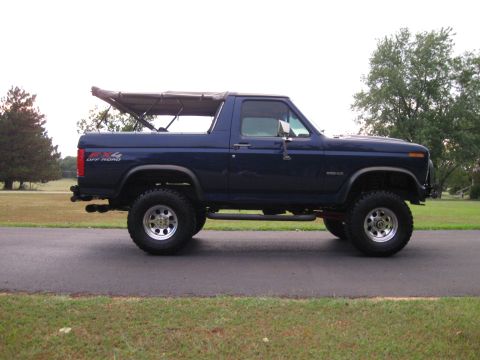 1982 Ford Bronco - This lifted blue Ford Bronco features a soft top and off-road tires, appearing to be from the early 1980s.