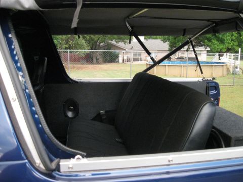 1982 Ford Bronco - Rear interior of a blue SUV with aftermarket audio equipment and a view of a backyard pool.