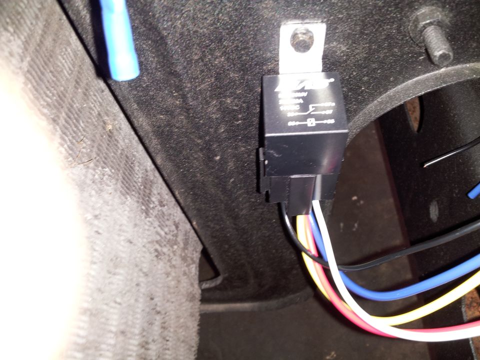 Automotive relay with multiple colored wires connected, mounted to a dark surface