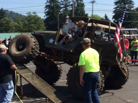 1989 Ford Bronco - A heavily modified off-road vehicle is positioned on a ramp with spectators observing the event.